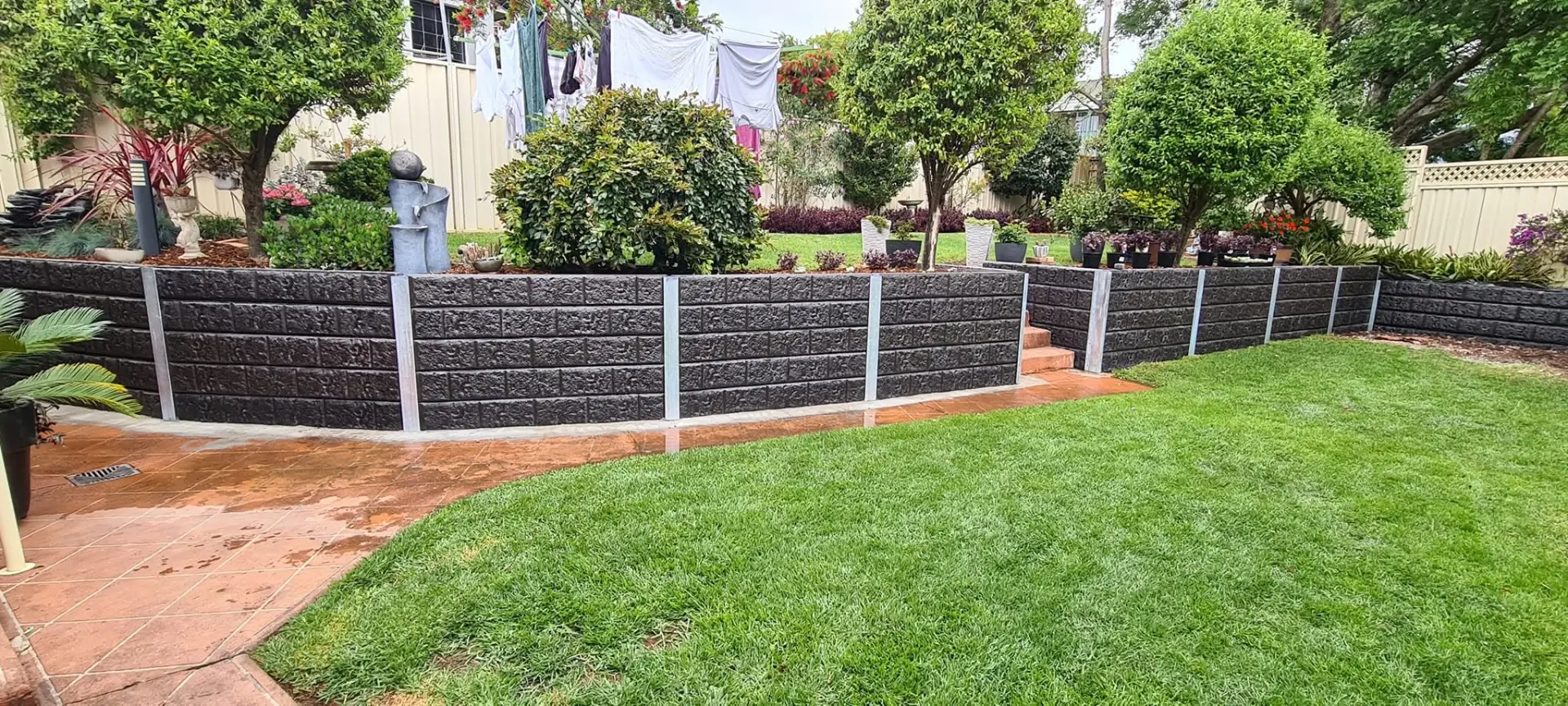 Tiered charcoal concrete sleeper retaining walls built by Retain by Theo in Wollongong